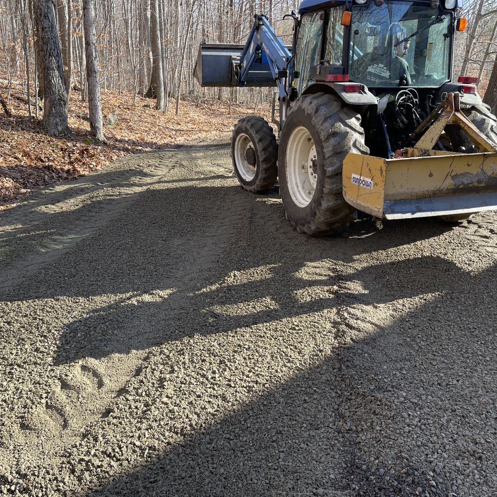 Freshly graded residential gravel driveway with smoother surface after pothole repair