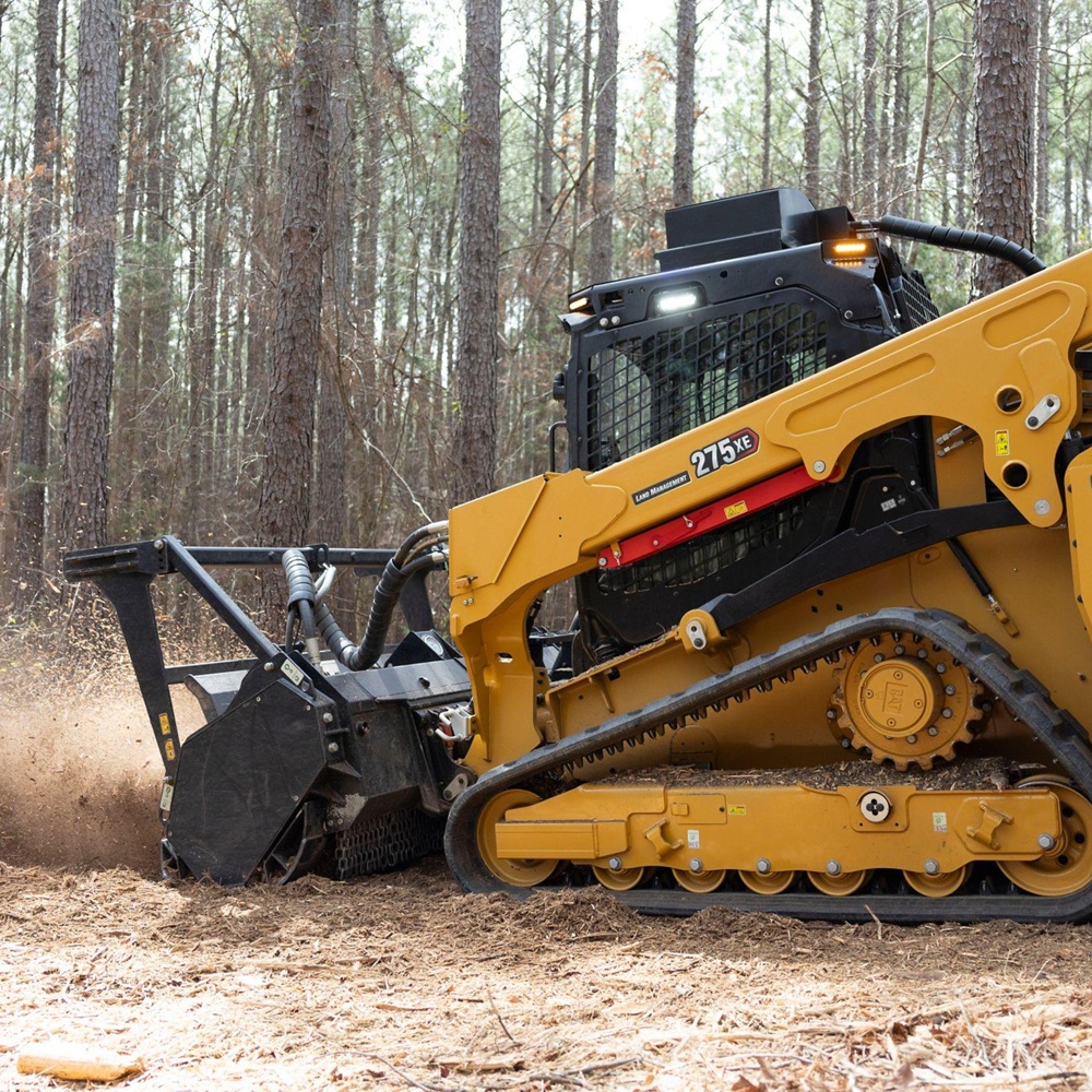 Operator using specialized mulching equipment to clear dense brush with controlled precision